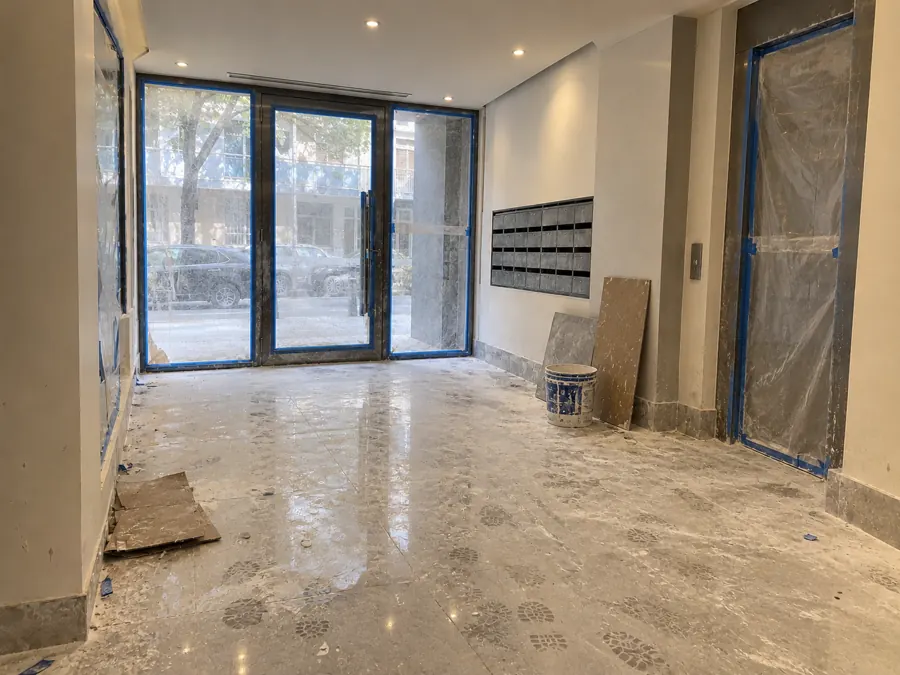 Antes: Hall de entrada del edificio de Boyacá, con polvo de obra, cinta y film en las aberturas