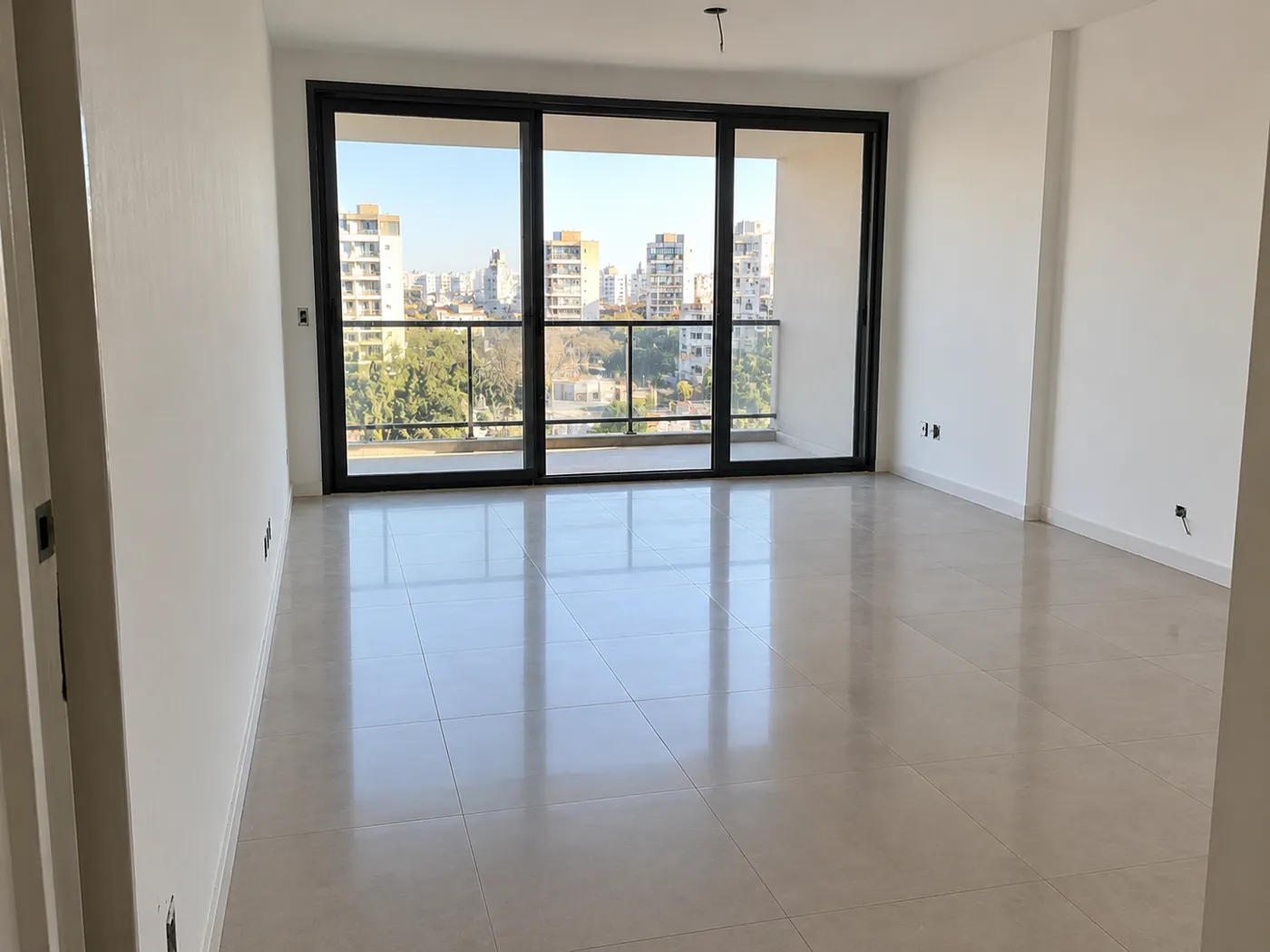 Living de un departamento a estrenar después de la limpieza final de obra, con el piso brillante y los vidrios limpios
